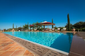 A swimming pool with lounge chairs and umbrellas, surrounded by trees and a clear sky. - Special Offer! Holidays, (Villa Lestra 8 + 3) Area Volterra, San Gimignano, Pisa (Pisa)