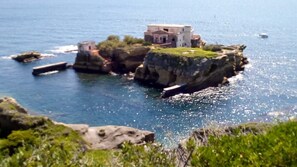 Ein Küstenhaus mit steinernen Fundamenten, umgeben von klarem, blauem Wasser.