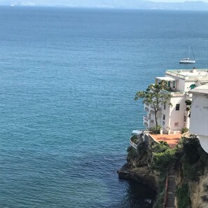 Ein Küstengebäude mit einer Treppe, die zum Meer hinabführt, mit Blick auf einen ruhigen Ozean.