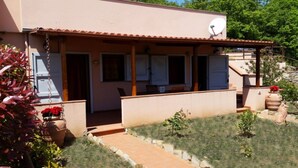 A two-story house with a covered patio, a satellite dish, and a small garden area with potted plants. - Horizons on the splendid Val di Cornia scenic two and comfortable  (Monteverdi Marittimo)