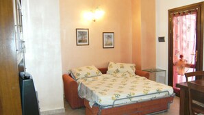 A small bedroom with a bed, a chair, a table, and a door. - Horizons on the splendid Val di Cornia scenic two and comfortable  (Monteverdi Marittimo)