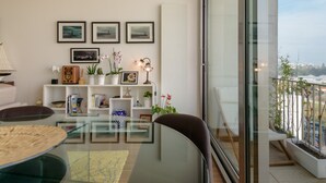 En moderne stue med et glasbord, en sofa, en reol med pynteting og en balkon med udsigt.