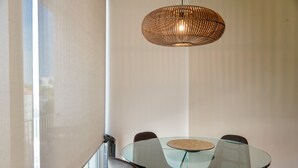 Et moderne spiseområde med et glasbord, brune stole og en vævet pendellampe.