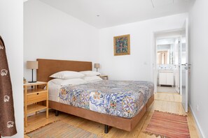 A bedroom with a bed, nightstand, and a door leading to a bathroom. - Chiado | COMFY & EASY ACCESS | Family-Friendly (Lisboa)