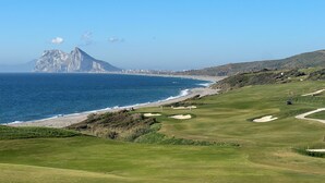 A coastal golf course with a view of the ocean and a mountain in the background. - A modern penthouse (110 m2) with sea and pool view, 3 bedrooms and 2 baths (Alcaidesa, San Roque, Sotogrande)