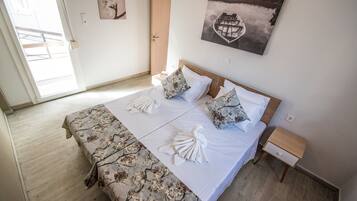 Una cama bien hecha con ropa de cama estampada con motivos florales, dos almohadas y una toalla doblada.