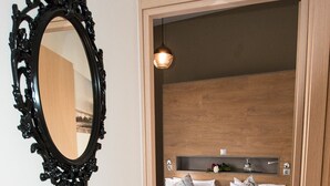 Una camera da letto con testiera in legno, un letto con biancheria da letto floreale, un comodino e uno specchio con cornice decorata.