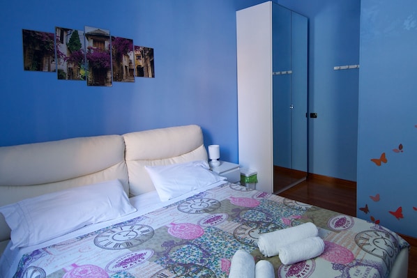 A bedroom with a bed, pillows, a clock-themed bedspread, a nightstand with a lamp, and a wardrobe. - Luxury Flat - CENTRAL - 4 Bedrooms - 2 Baths - Wi-Fi - A/C - Metro - Netflix (Roma)