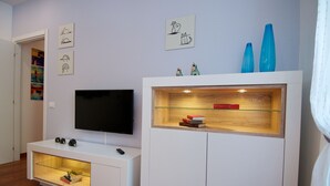Un salon moderne doté d’un téléviseur à écran plat, d’un meuble de rangement blanc et d’objets décoratifs.