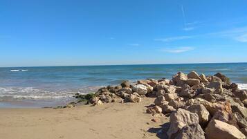 Enjoy a serene beach experience with a gentle sea and rocky shoreline.