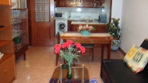 A kitchen with wooden cabinets, a dining table, and a coffee table with a vase of flowers. - Artur apartment with balcony (Lousã)