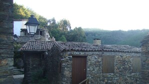 A rustic stone building with a tiled roof, wooden doors, and a lantern. - Artur apartment with balcony (Lousã)