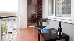 Een balkon met een tafel, stoelen, een fles wijn en een boek.