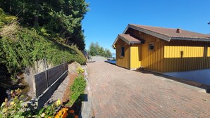 Un bâtiment jaune avec un toit en pente, un chemin pavé et une clôture en bois.