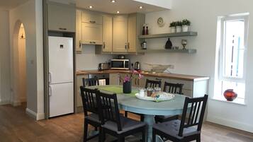 Una cocina moderna con zona de comedor, suelo de madera y electrodomésticos integrados.