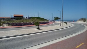 Une route sinueuse avec une piste cyclable rouge, un mur de pierre et un bâtiment avec un toit rouge.