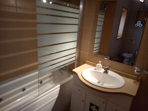 Une salle de bain avec une baignoire, un lavabo, un miroir et des toilettes.