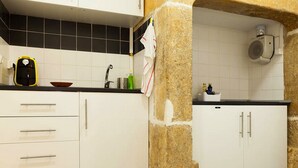 Une cuisine avec des armoires blanches, un comptoir noir et une colonne en pierre.