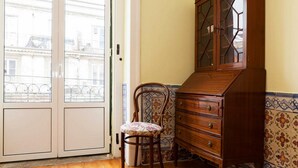 Une pièce avec un meuble en bois, une chaise et une porte donnant sur un balcon.