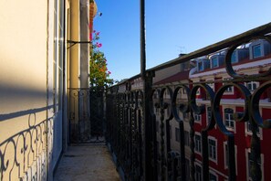 A narrow alleyway with a metal fence and a building with red and white facades. - Apartment Baixa/Chiado view Tagus (Lisboa)