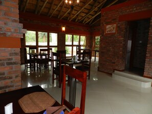 A restaurant with brick walls, large windows, and wooden furniture. - Kutandara Lodges (Harare)