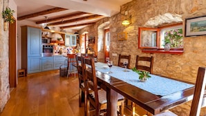 A rustic dining area with a wooden table and chairs, stone walls, and exposed wooden beams.