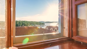 A view from an attic bedroom to the bay, featuring a wooden window frame and a glimpse of the surrounding buildings.