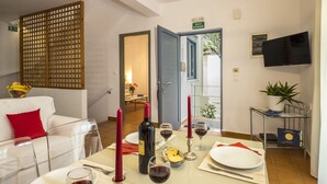 Comedor con una mesa preparada para dos personas, una botella de vino, copas y un frutero.