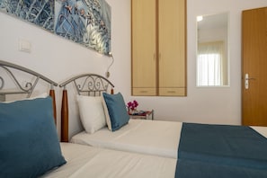 A bedroom with a bed, a nightstand, a wardrobe, a painting, and a mirror.