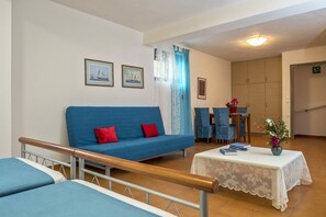 A room with a blue sofa, a small table with books, a chair, and a cabinet. - Giannis Beach villa in Almirida,no car needed (Almyrida)