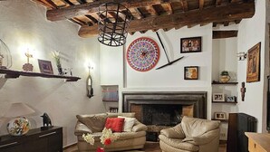 Uma sala de estar acolhedora com lareira, sofás de couro, uma mesa de centro e vigas de madeira rústicas no teto.