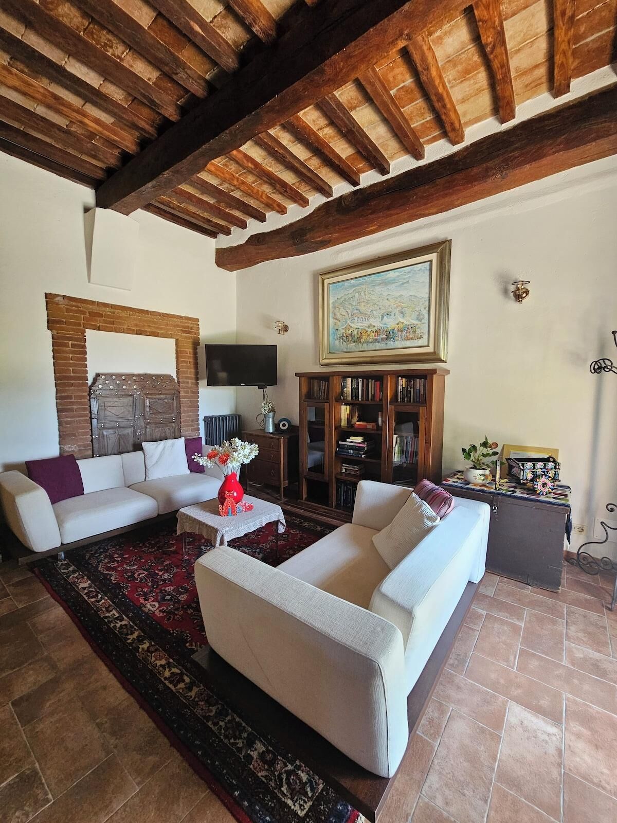 A living room with a fireplace, sofas, a television, and a bookshelf.