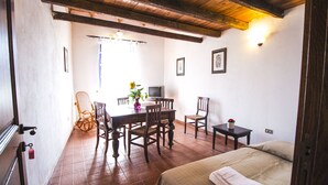 A room with a bed, a dining table with chairs, a small table with a lamp, and a television. - Holiday apartment in the mountains and lake in a period house in the medieval village I Cardi (Poggio San Giovanni)