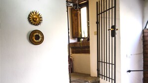A staircase leading to a door with a metal gate, a welcome sign, and a sun-shaped decoration on the wall. - Holiday apartment in the mountains and lake in a period house in the medieval village I Cardi (Poggio San Giovanni)