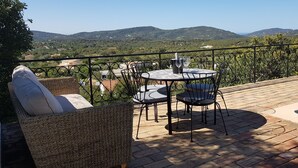 En terrasse med et bord og stole, en pool og udsigt til bakker.
