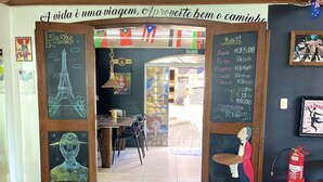 A restaurant entrance with a chalkboard menu, Eiffel Tower drawing, and a figure holding a sign. - Hostel Casa do Rogerio (Caxias do Sul)