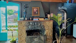A cozy room with a stone fireplace, wooden ceiling, and a view of the outside. - Hostel Casa do Rogerio (Caxias do Sul)