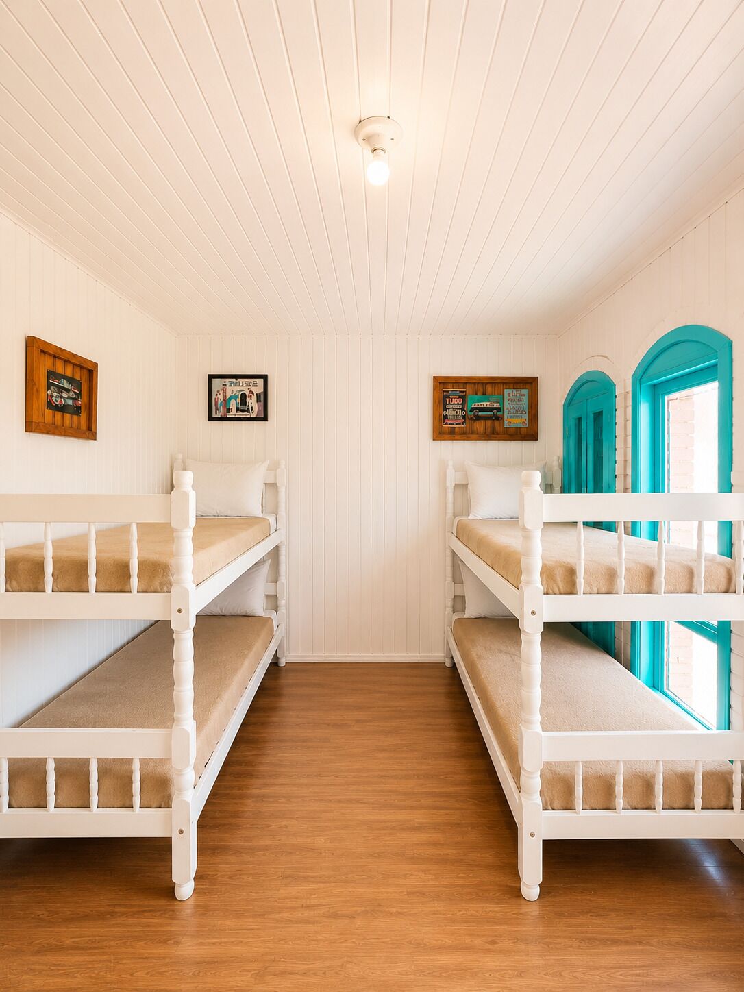 Una habitación con dos literas, piso de madera, paredes blancas y una lámpara en el techo.