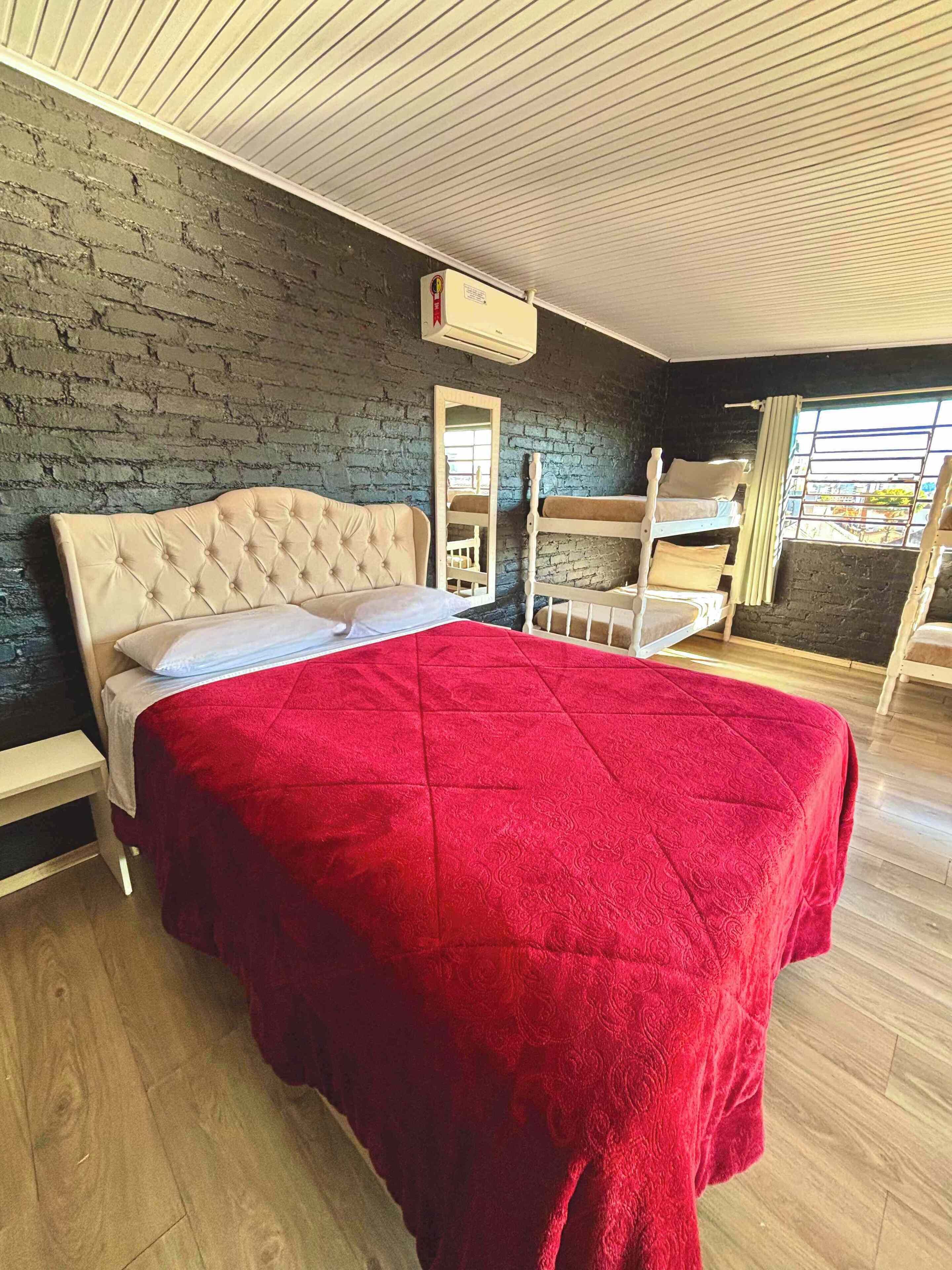Een slaapkamer met een groot bed, een houten bankje, een spiegel en een raam met uitzicht.
