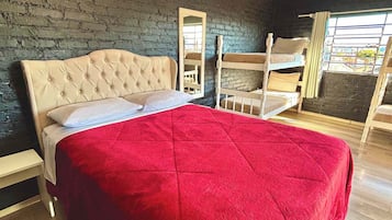 Een slaapkamer met een groot bed, een houten bankje, een spiegel en een raam met uitzicht.