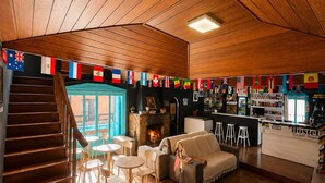 A wooden interior with a staircase, a sofa, a bar area, and a fireplace. - Hostel Casa do Rogerio (Caxias do Sul)