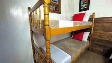 Uma cama beliche com grades de madeira e cabeceira, roupa de cama branca e almofadas vermelhas.