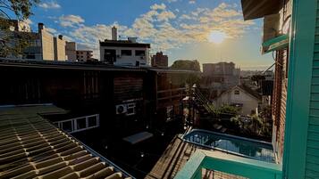 Um terraço no telhado com piscina, vista para a cidade e céu claro.