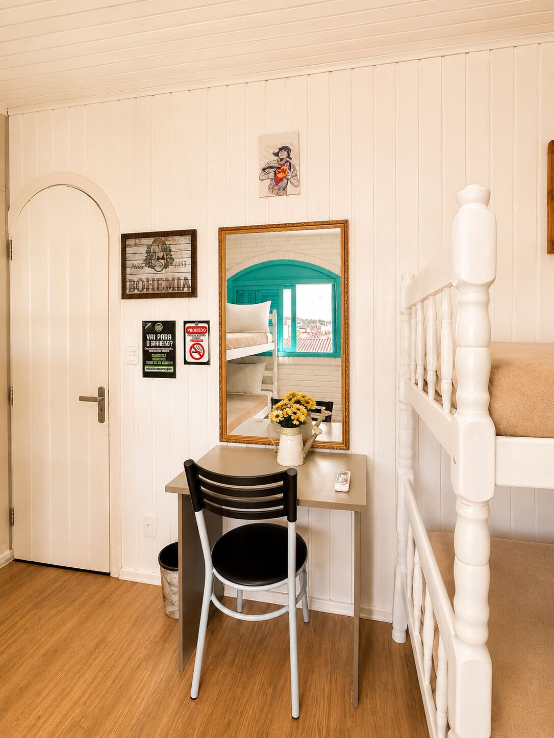 A room with a desk, chair, bunk bed, and a door.