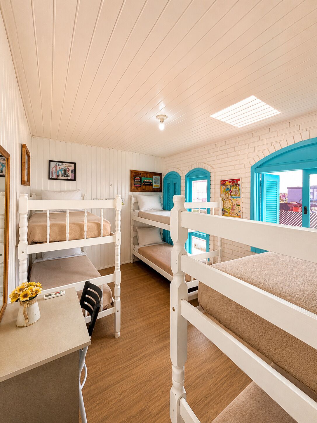 A bunk bed room with a desk, a chair, and a vase with flowers.