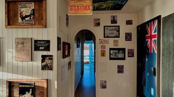 Un pasillo con paredes y suelo de madera, decorado con varios carteles y anuncios, incluyendo un letrero de cerveza Brahma y un anuncio de neumáticos Michelin.