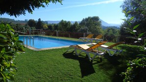 Piscina com espreguiçadeiras e deck de madeira.