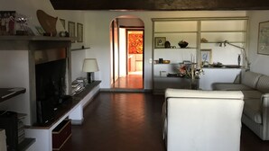 Una sala de estar con chimenea, un sofá, un televisor y un comedor con mesa y sillas.