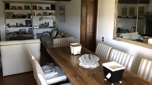 Un comedor con mesa de madera, sillas a rayas y un espejo grande.