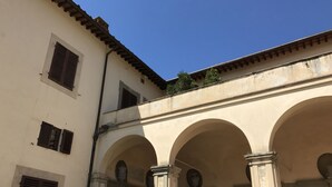 Un edificio con un patio que presenta arcos y columnas, un tejado de azulejos y un pequeño jardín.